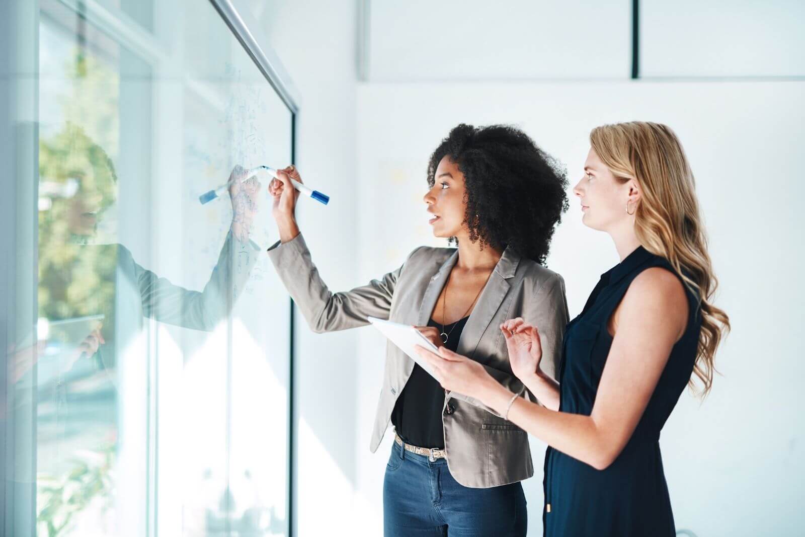 Professional branding strategy session for graphic design & branding in Torrance, CA with two businesswomen reviewing visual concepts on glass board